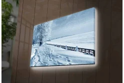 Canvastavla med LED-belysning - Snöklädd vinterlandskap med fotspår och träddunge