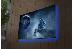 Canvastavla med LED-belysning 45x70 cm - Astronaut som sitter på en klippa och blickar ut mot jorden i rymden