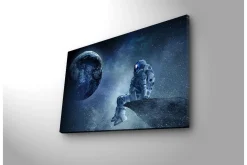 Canvastavla med LED-belysning - Astronaut som sitter på en klippa med jorden i bakgrunden