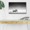 Canvastavla med LED-belysning - Svartvit bild av en elefant som går genom savannen med en zebra i bakgrunden