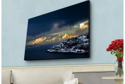 Canvastavla med LED-belysning - Dramatiskt kustlandskap med snöklädda klippor och mörka moln