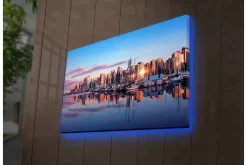Canvastavla med LED-belysning - Stadssilhuett vid solnedgång med reflektioner i vattnet