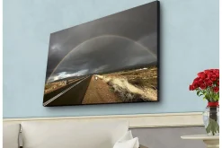 Canvastavla med LED-belysning - Regnbåge som sträcker sig över en mörk himmel ovanför en landsväg