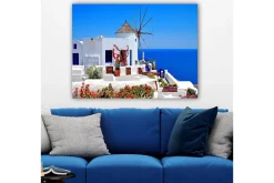 Canvastavla 70x100 cm - Pittoresk vy av en vitkalkad byggnad med en traditionell vindmölla och färgglada blommor i Santorini