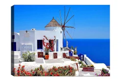 Canvastavla 70x100 cm - Pittoresk vy av en vitkalkad byggnad med en traditionell vindmölla och färgglada blommor i Santorini