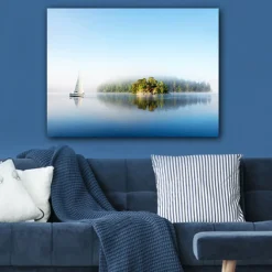 Canvastavla 70x100 cm - Segelbåt glider fram över en spegelblanka sjö med en dimmig ö i bakgrunden