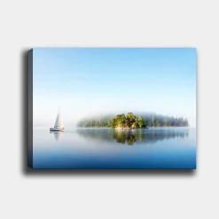 Canvastavla 70x100 cm - Segelbåt glider fram över en spegelblanka sjö med en dimmig ö i bakgrunden