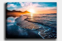 Canvastavla 70x100 cm - Solnedgång över en strand med mjuka vågor som rullar in mot kusten