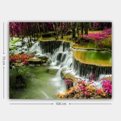 Canvastavla 70x100 cm - Vacker vattenfallsscen omgiven av färgglada blommor och grönskande träd